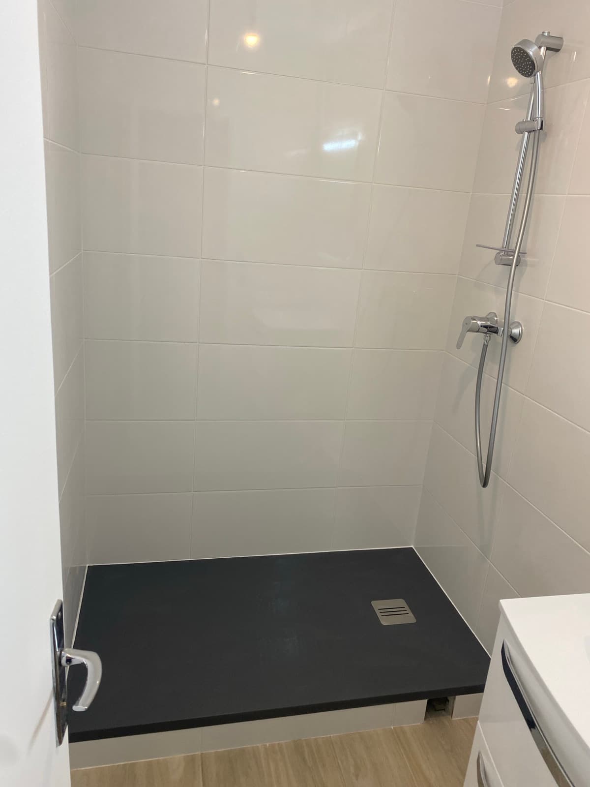 Douche italienne finie — carrelage mural blanc brillant et colonne chromée