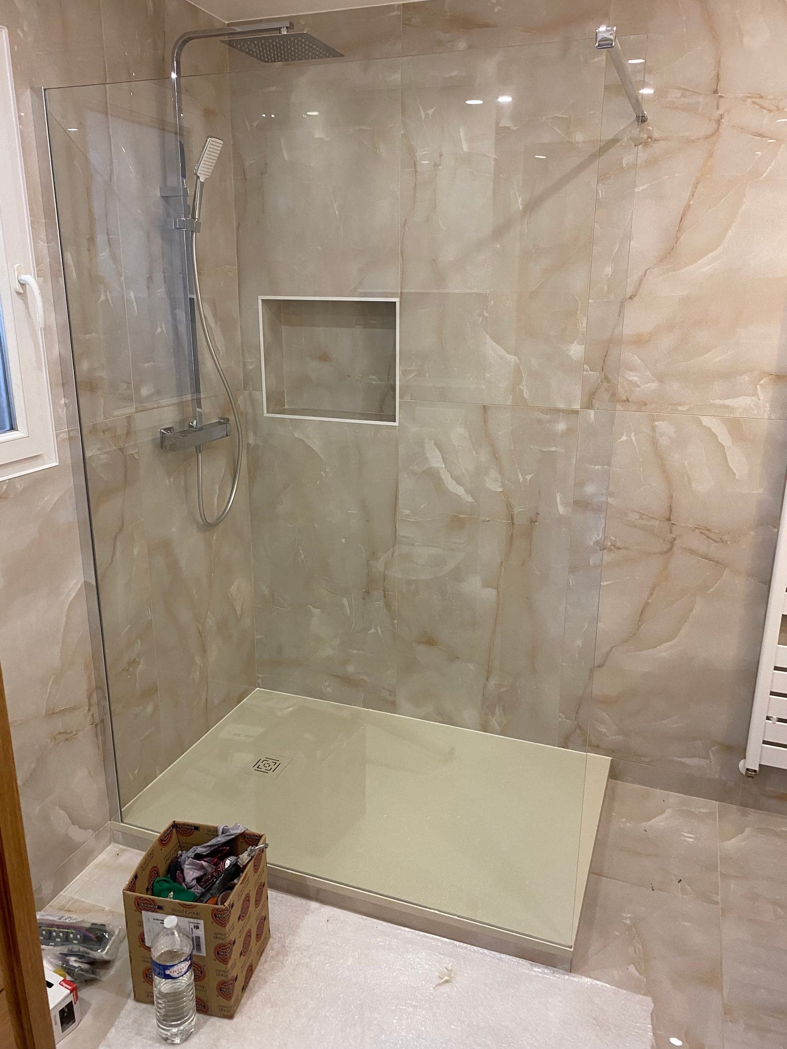 Douche italienne finie — paroi verre, mur effet marbre onyx beige, niche encastrée